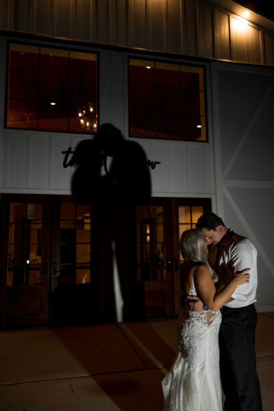 Intimate romantic night portrait of bride and groom outside The Willow entrance with illuminated silhouette shadow