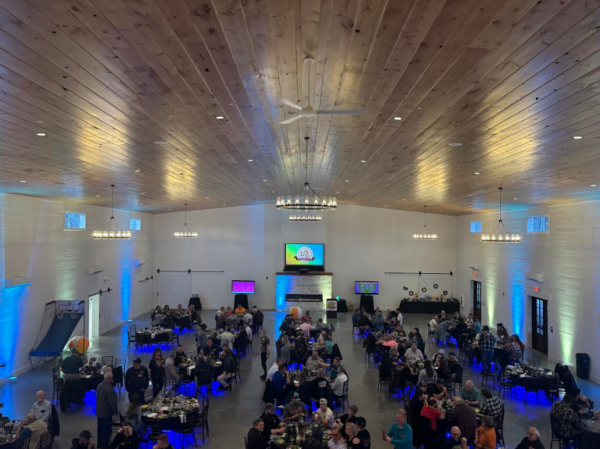 Wide elevated view of guests seated at dinner tables during a large corporate and social event in the grand hall