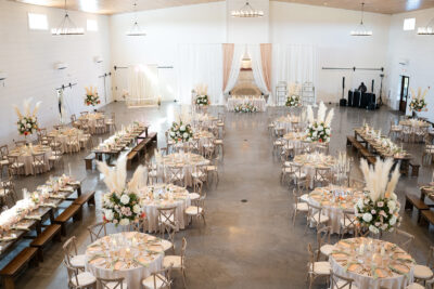 Wide overhead view of the grand reception hall styled with pampas grass centerpieces and draped backdrop