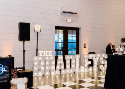 Illuminated The Bradleys marquee letters alongside the checkered dance floor during a winter wedding