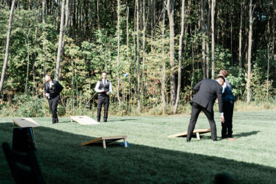 Groomsmen playing cornhole lawn games on the patio grounds surrounded by Pennsylvania woodland