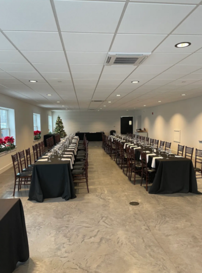 Long parallel banquet dining tables with black tablecloths and Chiavari chairs in the Side Room