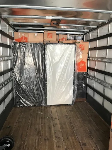 Mattresses sealed in heavy protective plastic and boxed goods stacked in moving truck