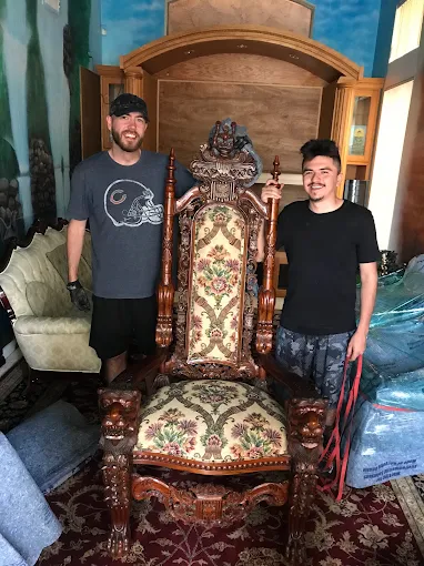 The Moving Guy movers posing proudly with a finely carved antique throne chair