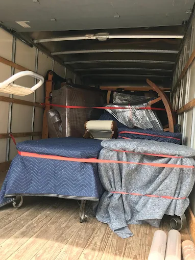 Moving truck packed and strapped with protective furniture blankets and tie downs