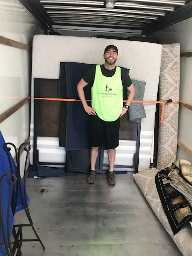 The Moving Guy mover in official high-vis vest smiling inside a loaded moving truck