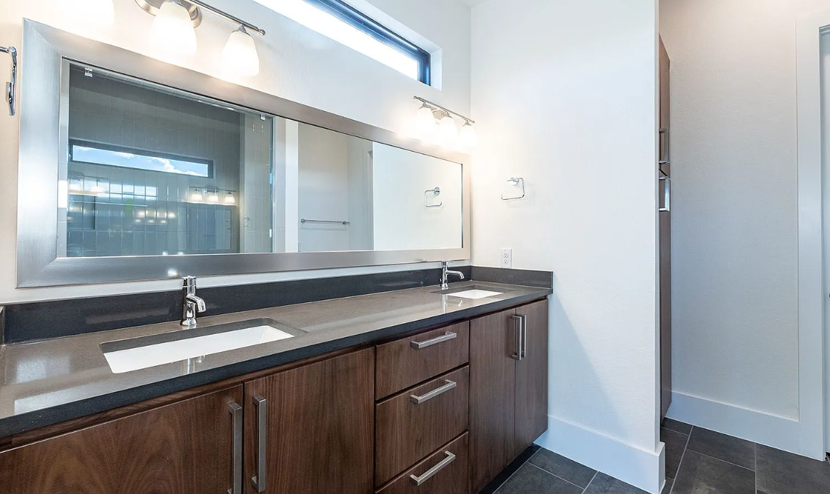 Primary suite luxury bath with dual vanity, warm walnut cabinetry, and designer fixtures