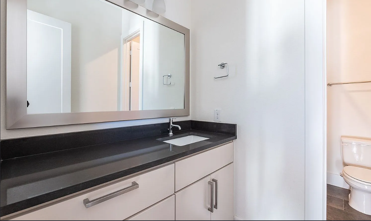 Full guest bathroom with expansive framed mirror and modern granite vanity