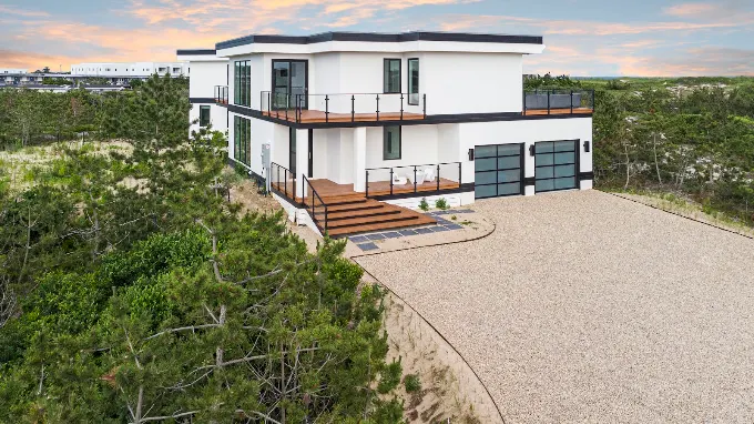 Contemporary oceanfront home with a cantilevered deck and glass garage doors built by Custom Island Homes