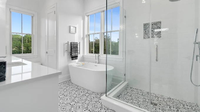 Primary bathroom with a freestanding soaking tub, glass shower enclosure and patterned tile flooring