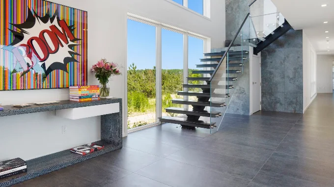 Two story entry with a floating steel staircase and large format porcelain tile flooring