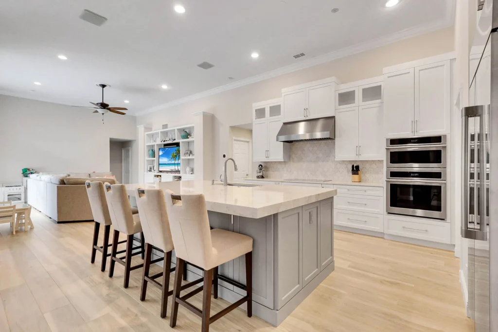 White shaker kitchen remodel with a large grey island and double wall ovens by Stuart Kitchen Bath and Flooring