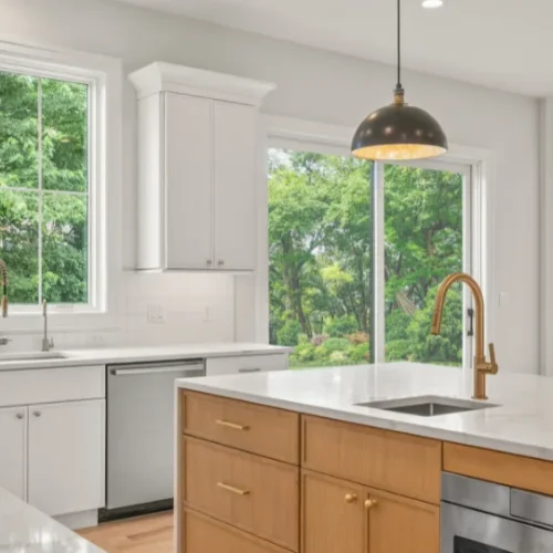 White kitchen remodel with a light wood island and brass fixtures by Stuart Kitchen Bath and Flooring