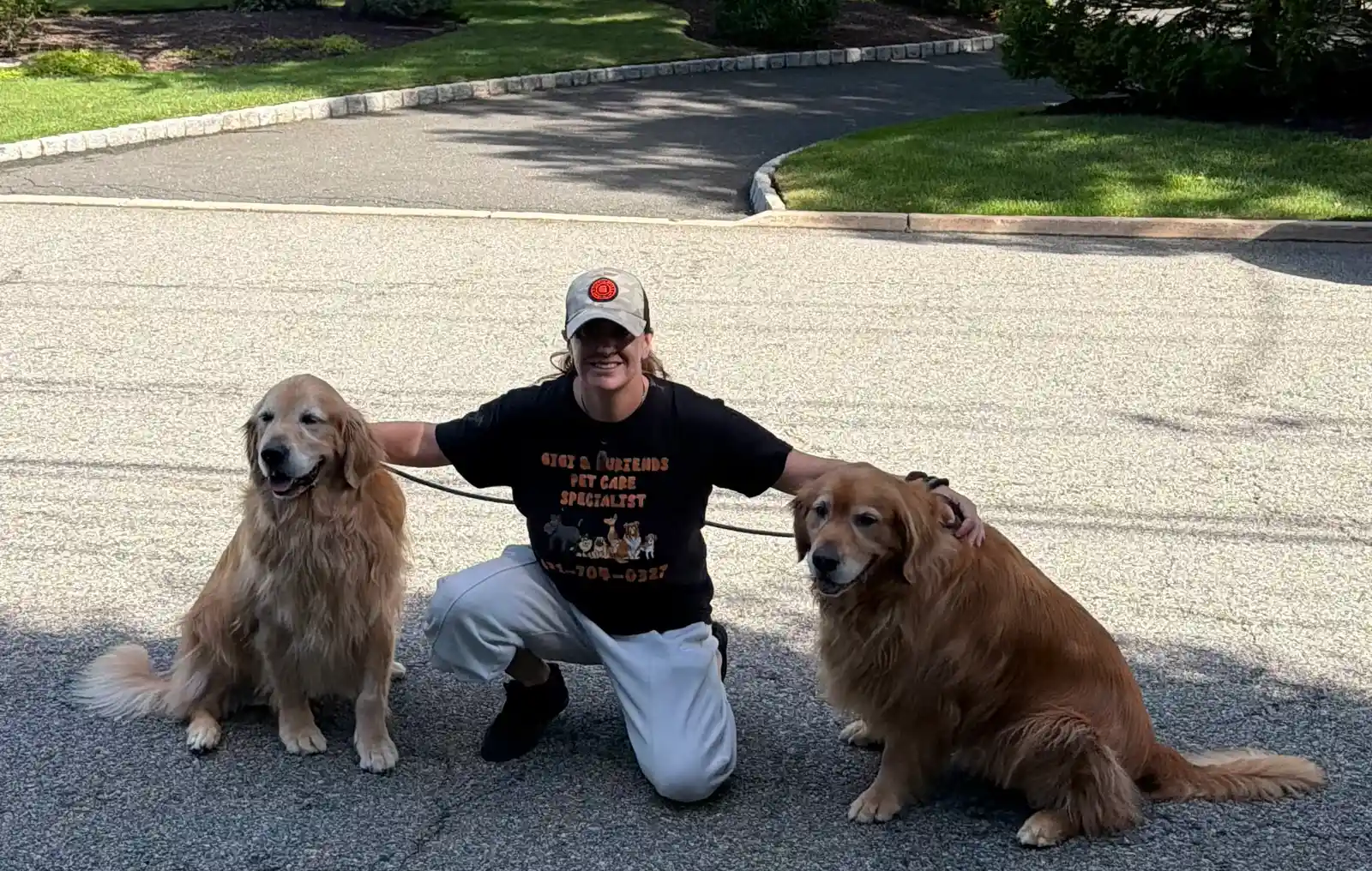 Super Gigi kneeling proudly between two senior golden retrievers on paved driveway — Super Gigi pet sitting and dog walking in Bergen County, NJ