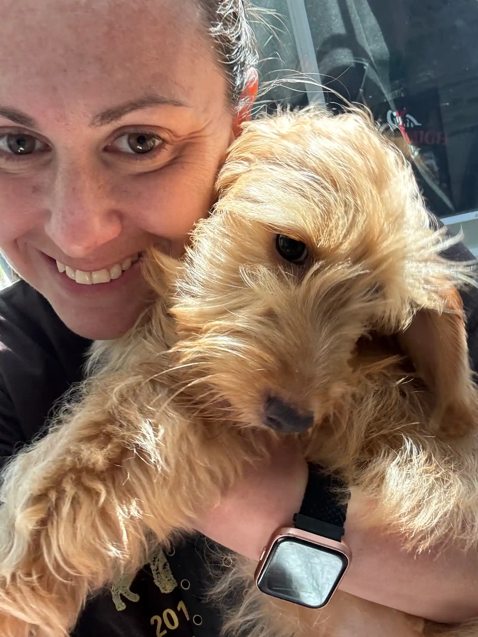 Geralin Rose Giorgio, founder and pet sitter Super Gigi, smiling warmly with a happy golden scruffy pup during in-home pet care in Bergen County NJ