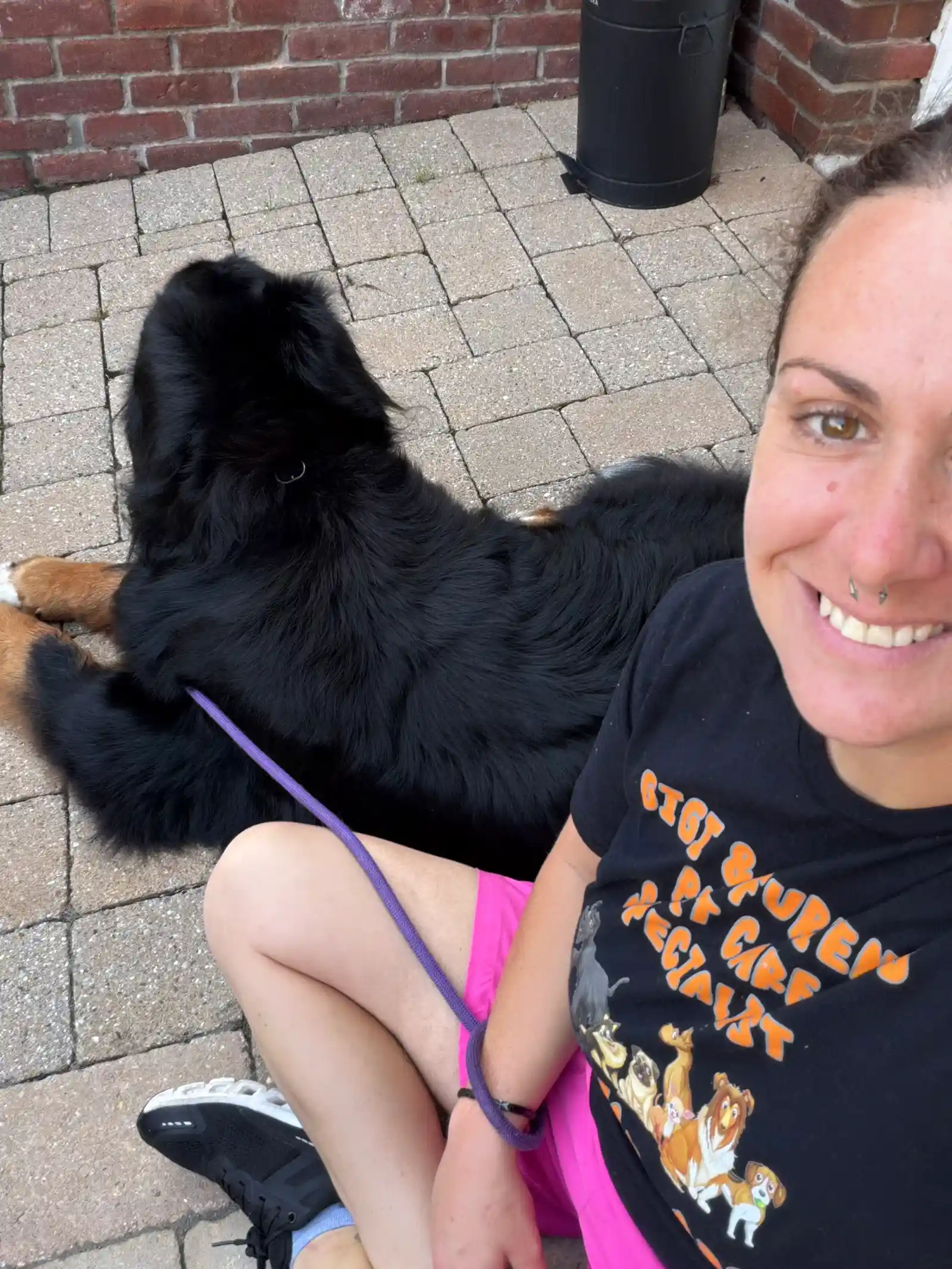 Super Gigi sitting happily on patio pavers with majestic Bernese mountain dog — Super Gigi pet sitting and dog walking in Bergen County, NJ