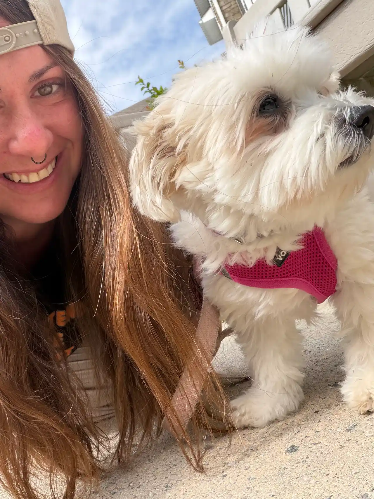 Super Gigi selfie smiling with fluffy white pup in pink harness — Super Gigi pet sitting and dog walking in Bergen County, NJ