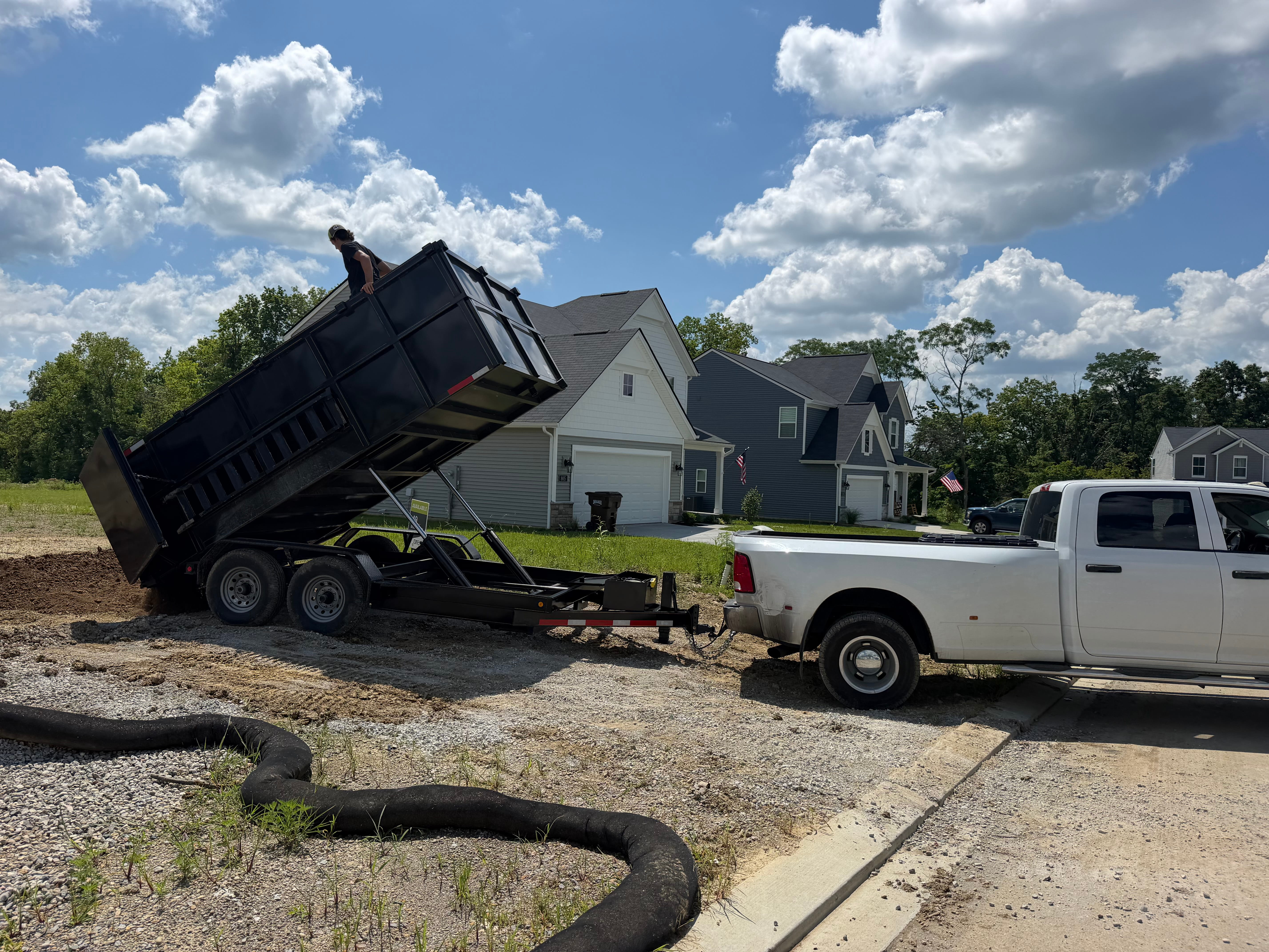 Hydraulic dump trailer unloading fill dirt for site grading and leveling