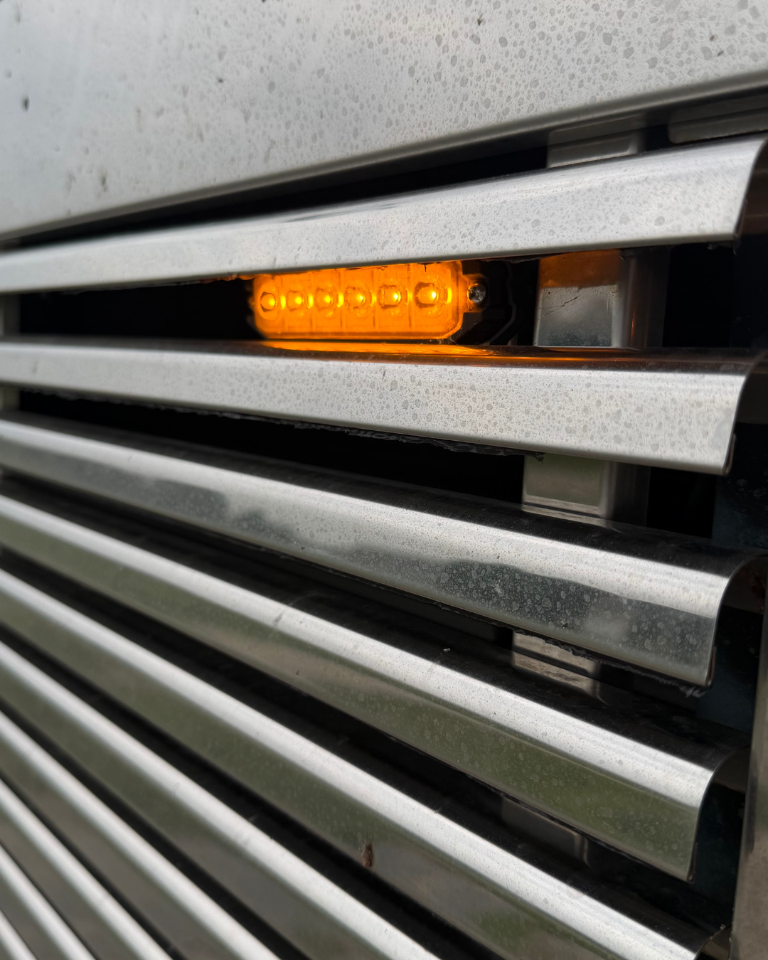 Amber LED grille strobe light flush-mounted into chrome truck grille bars
