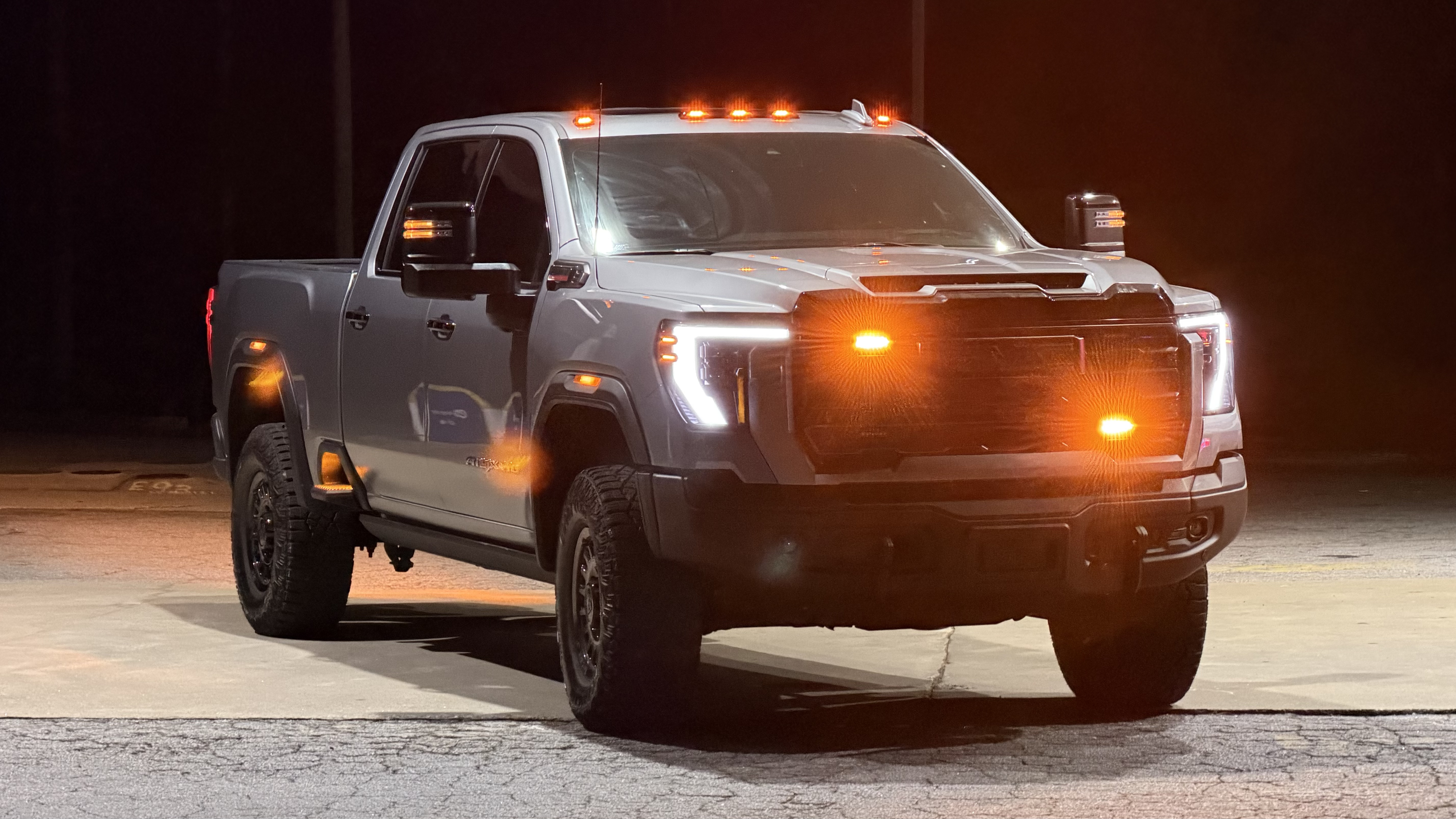 GMC AT4 heavy-duty pickup with high-output amber grille warning strobes and cab clearance lights at night