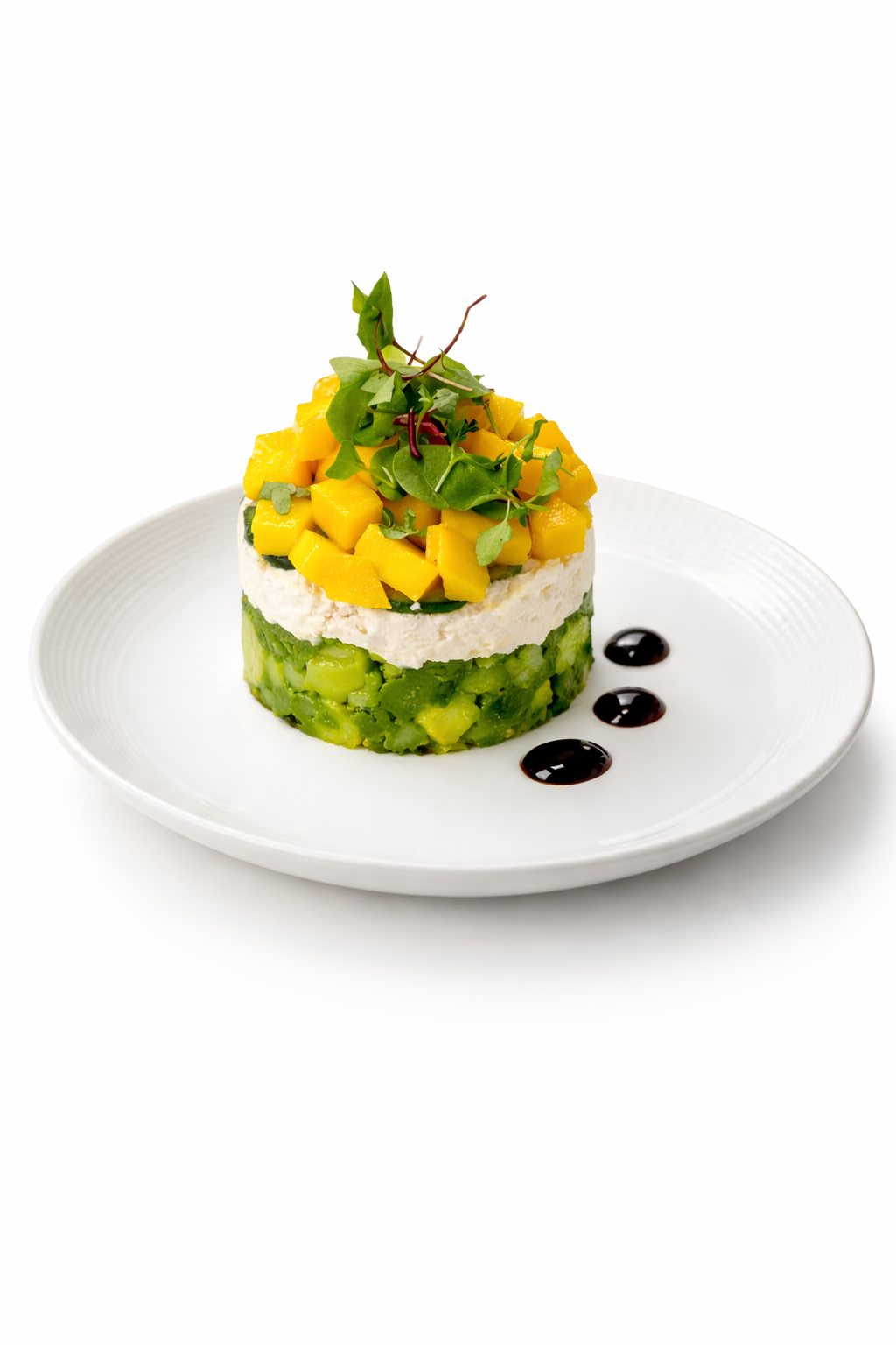 Layered avocado, crab or chicken salad, and diced mango timbale with microgreens
