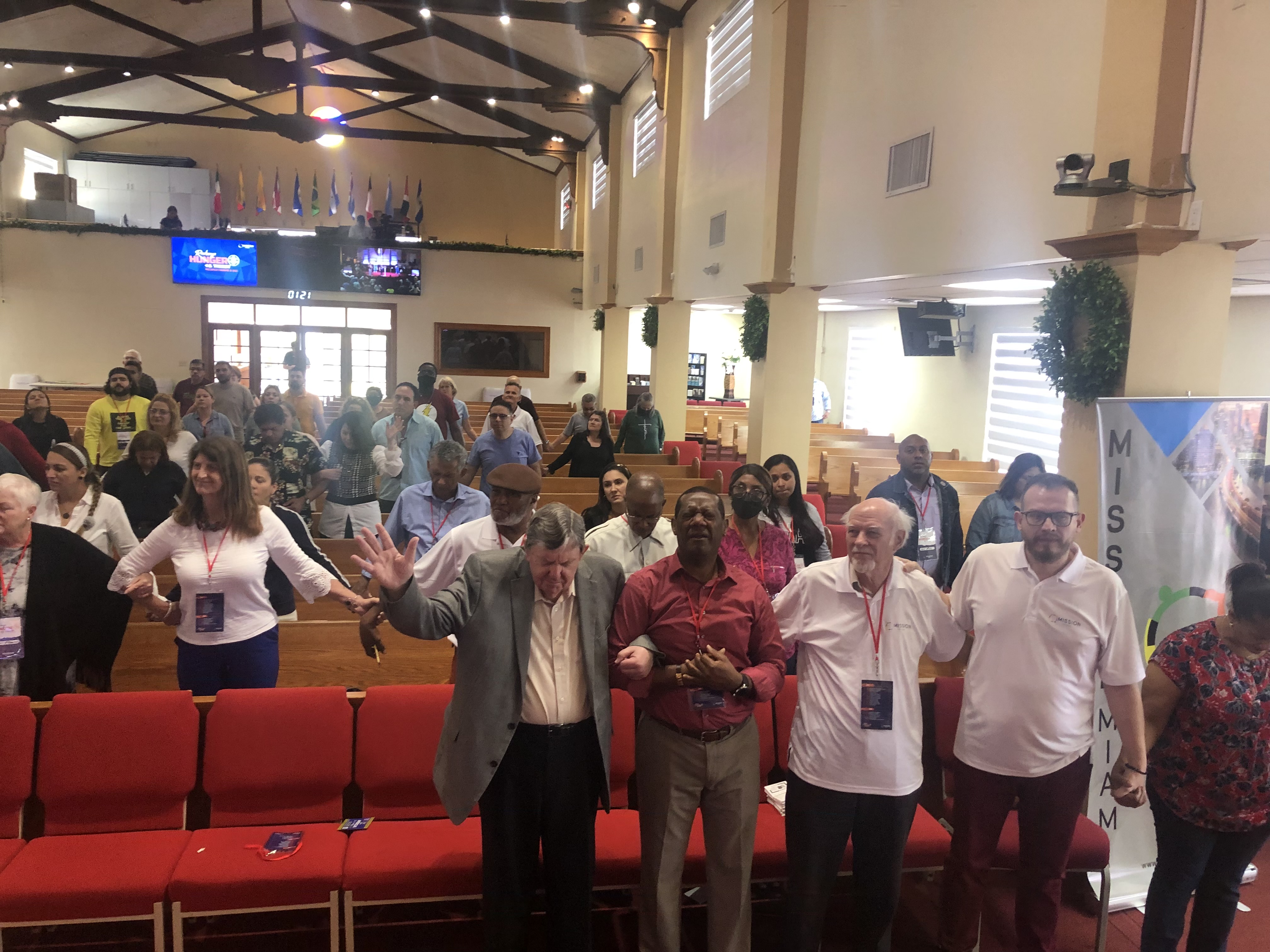 Congregation and leaders holding hands in united prayer at Recharge