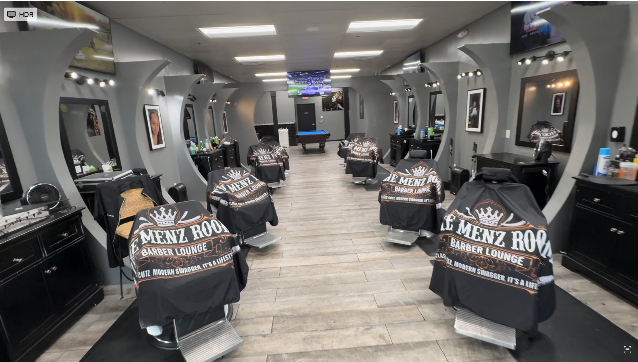 The Menz Room Barber Lounge interior with custom crescent chairs, mirrors, and lounge area
