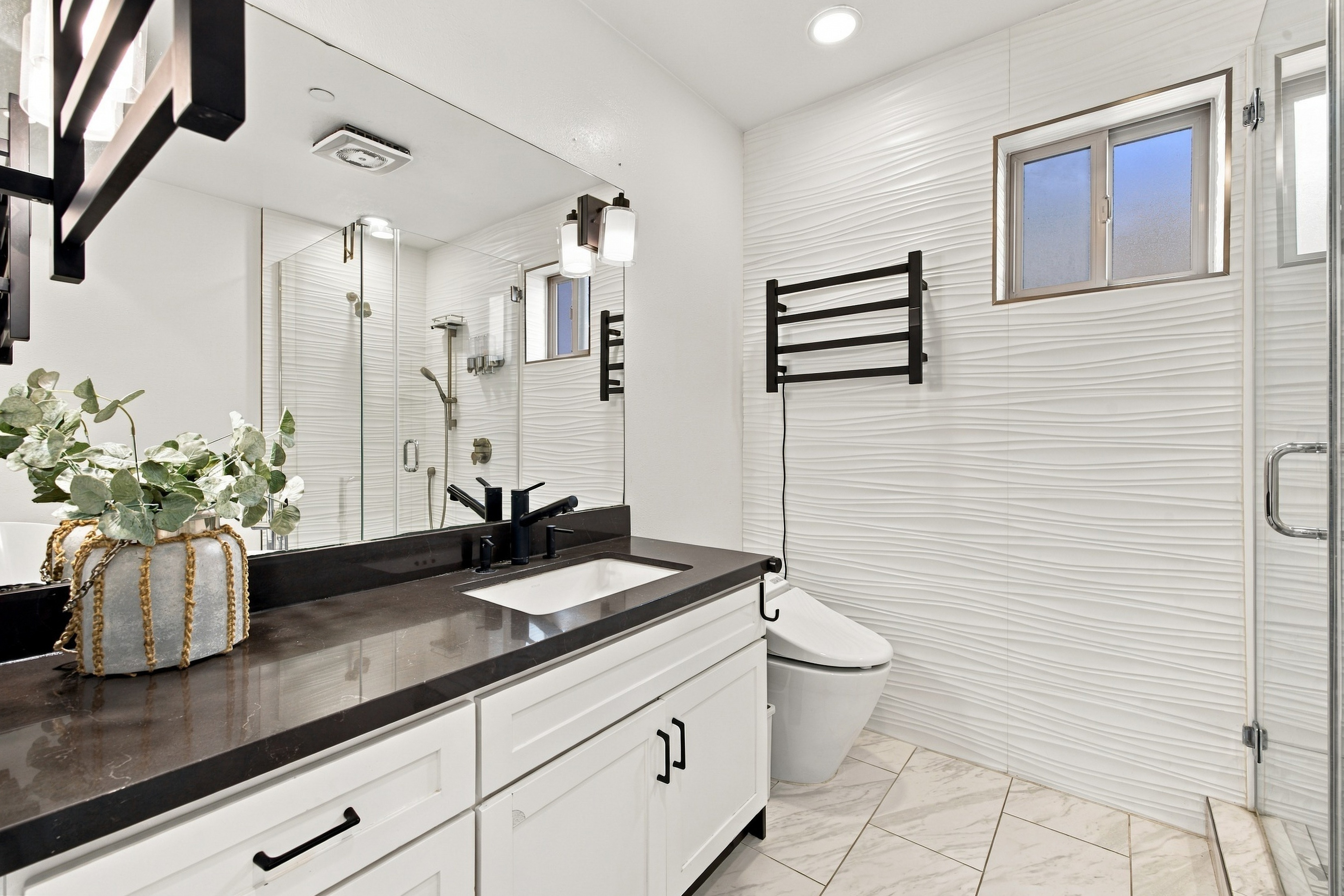 Primary ensuite bath with modern dark vanity and textured feature wall