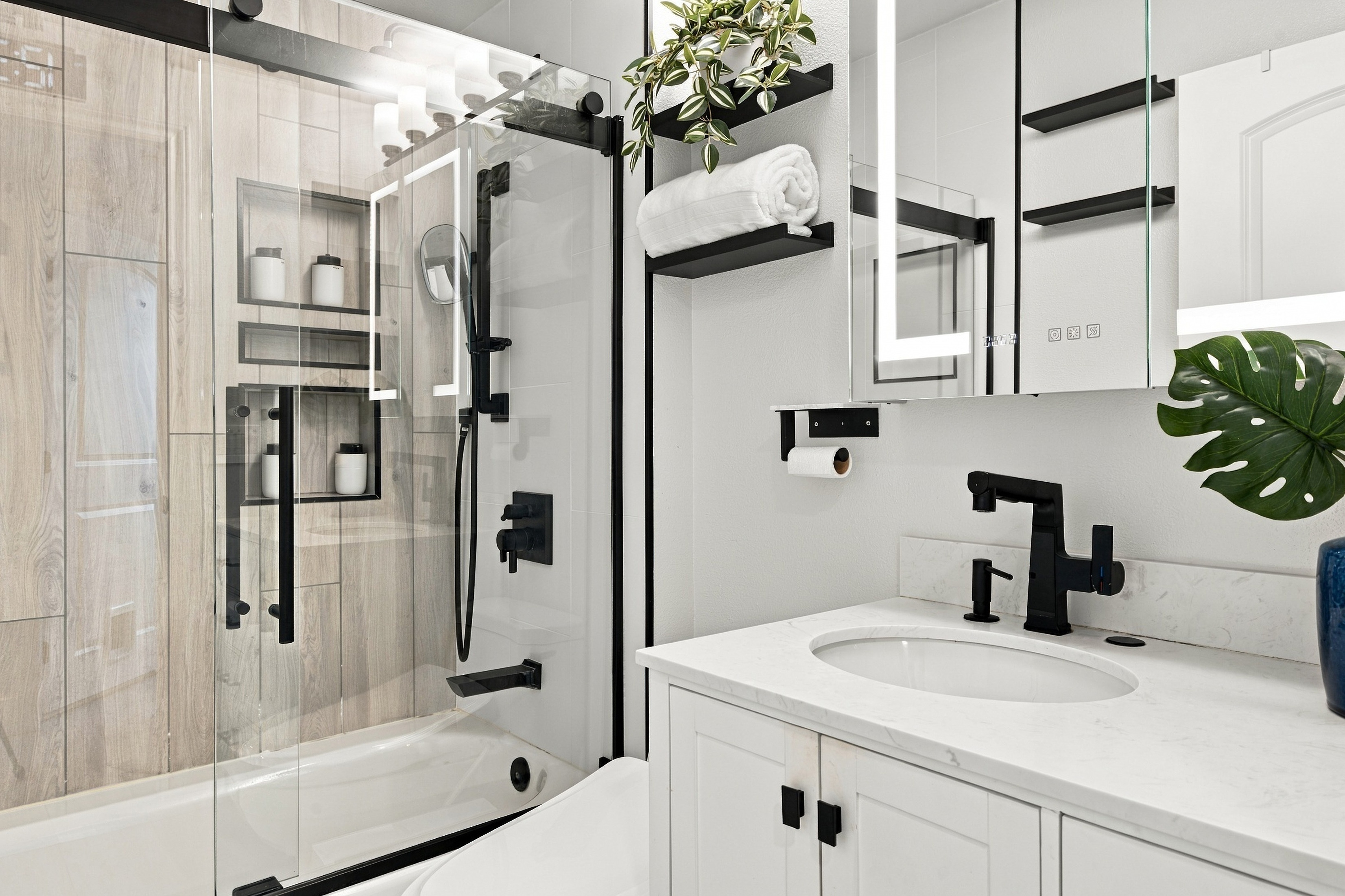 Updated bathroom vanity with black matte hardware and LED mirror