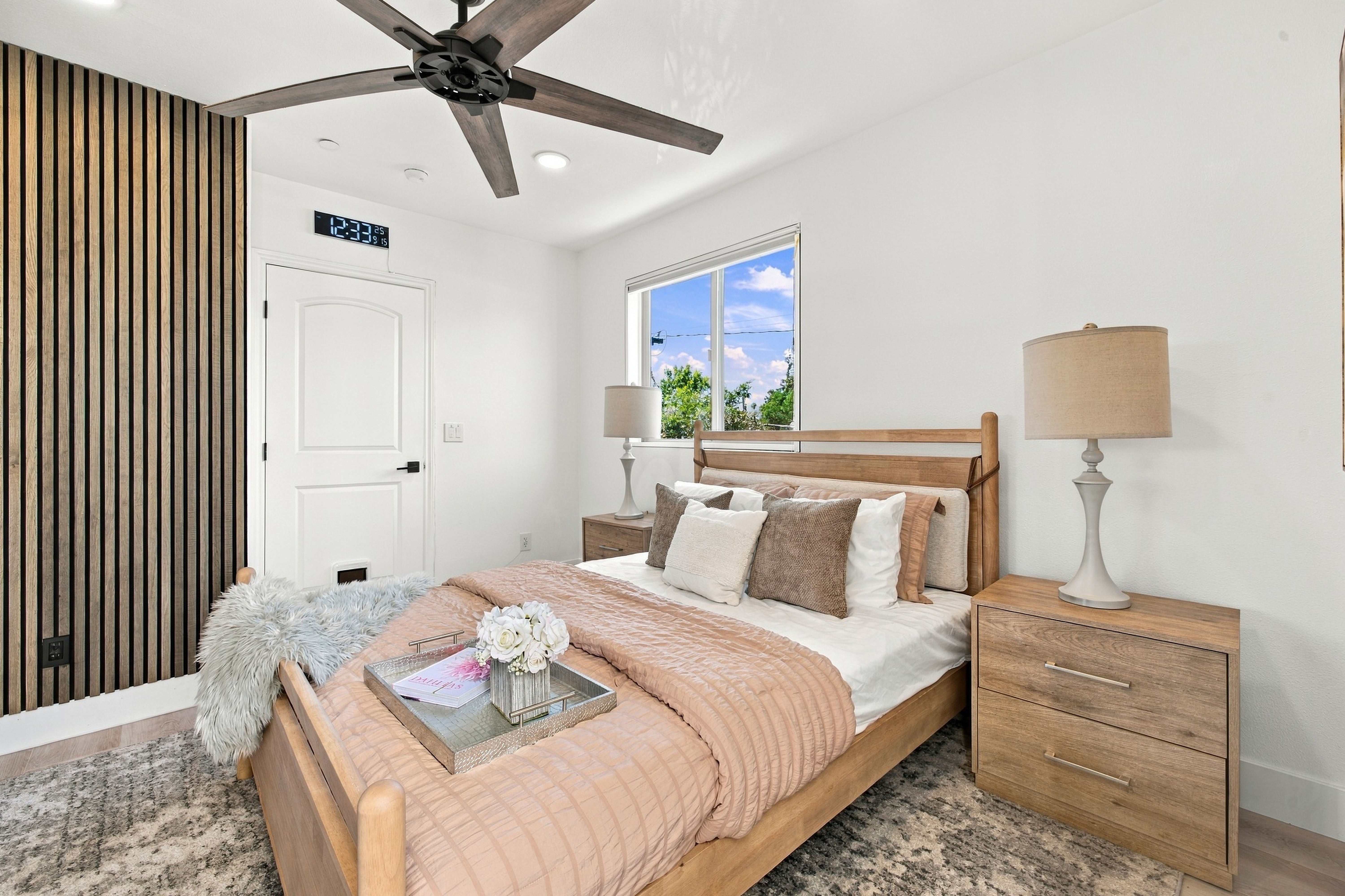 Bright second bedroom with vertical wood slat accent and wood ceiling fan
