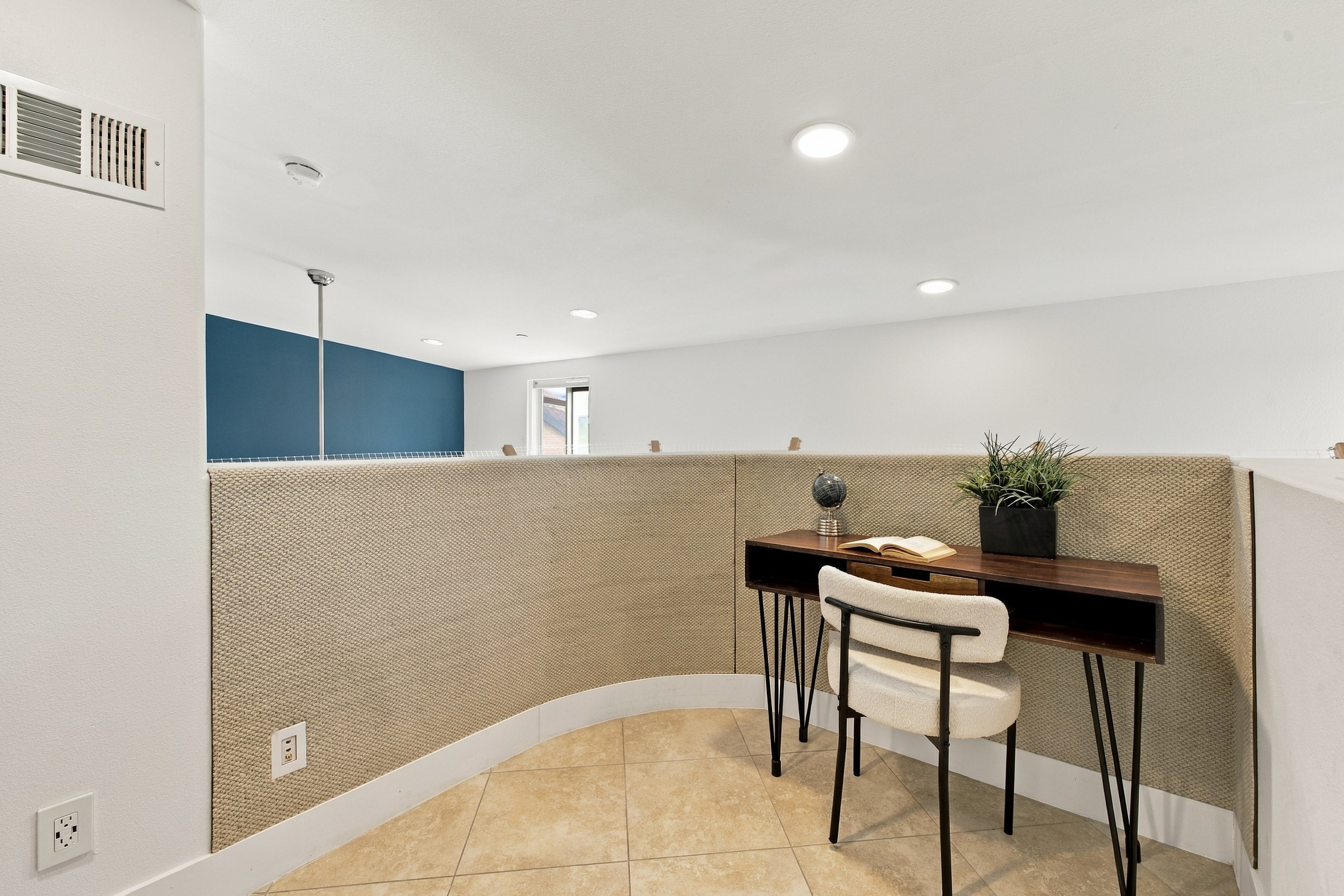 Dedicated loft workspace and office nook with curved textured wall and desk