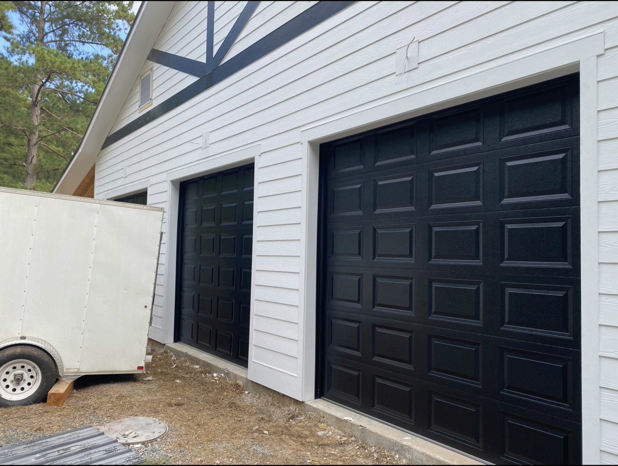 Installed black residential garage doors on a modern white-sided home by All Access Garage Doors