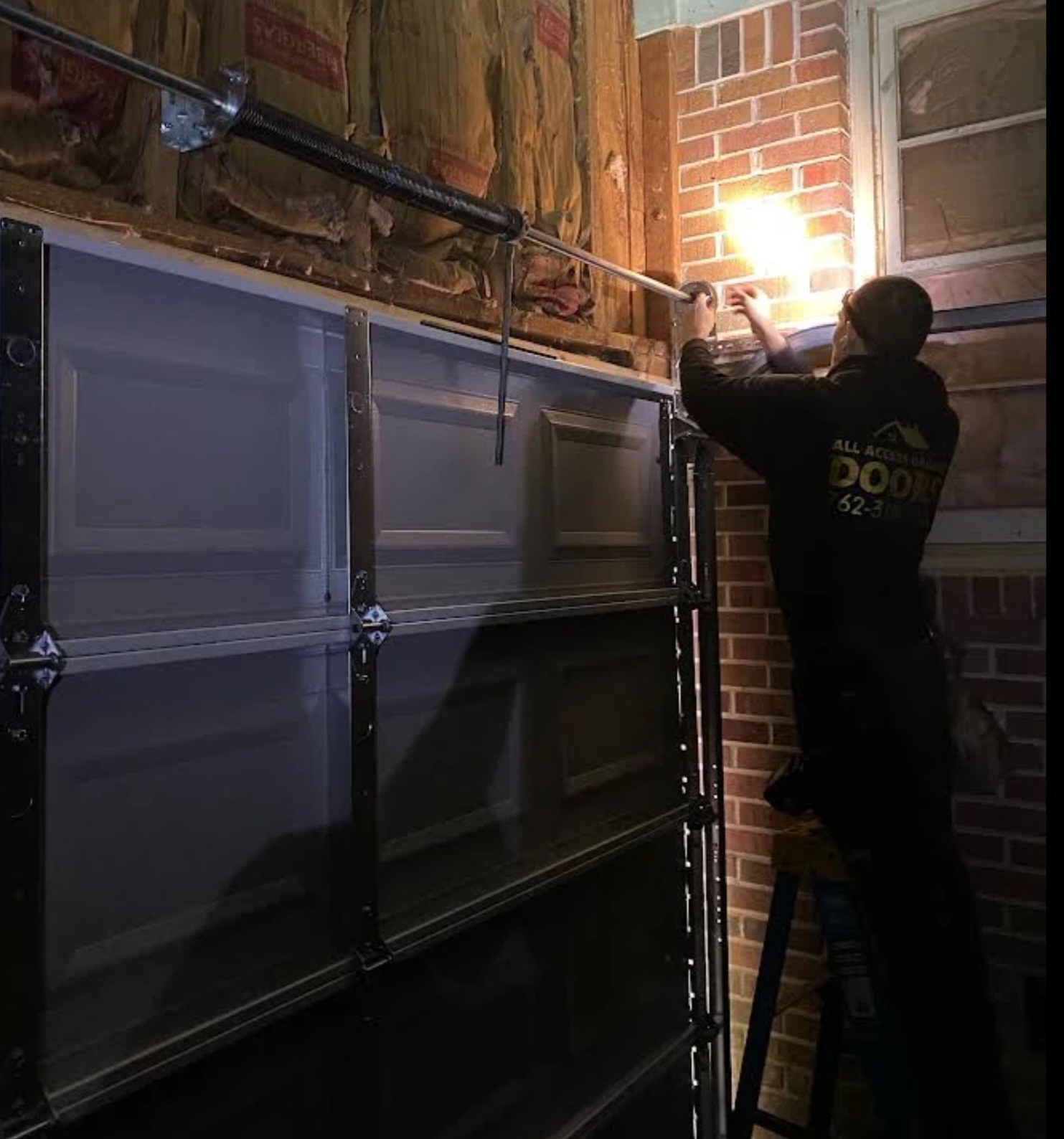 All Access Garage Doors technician repairing residential garage door torsion spring and track assembly