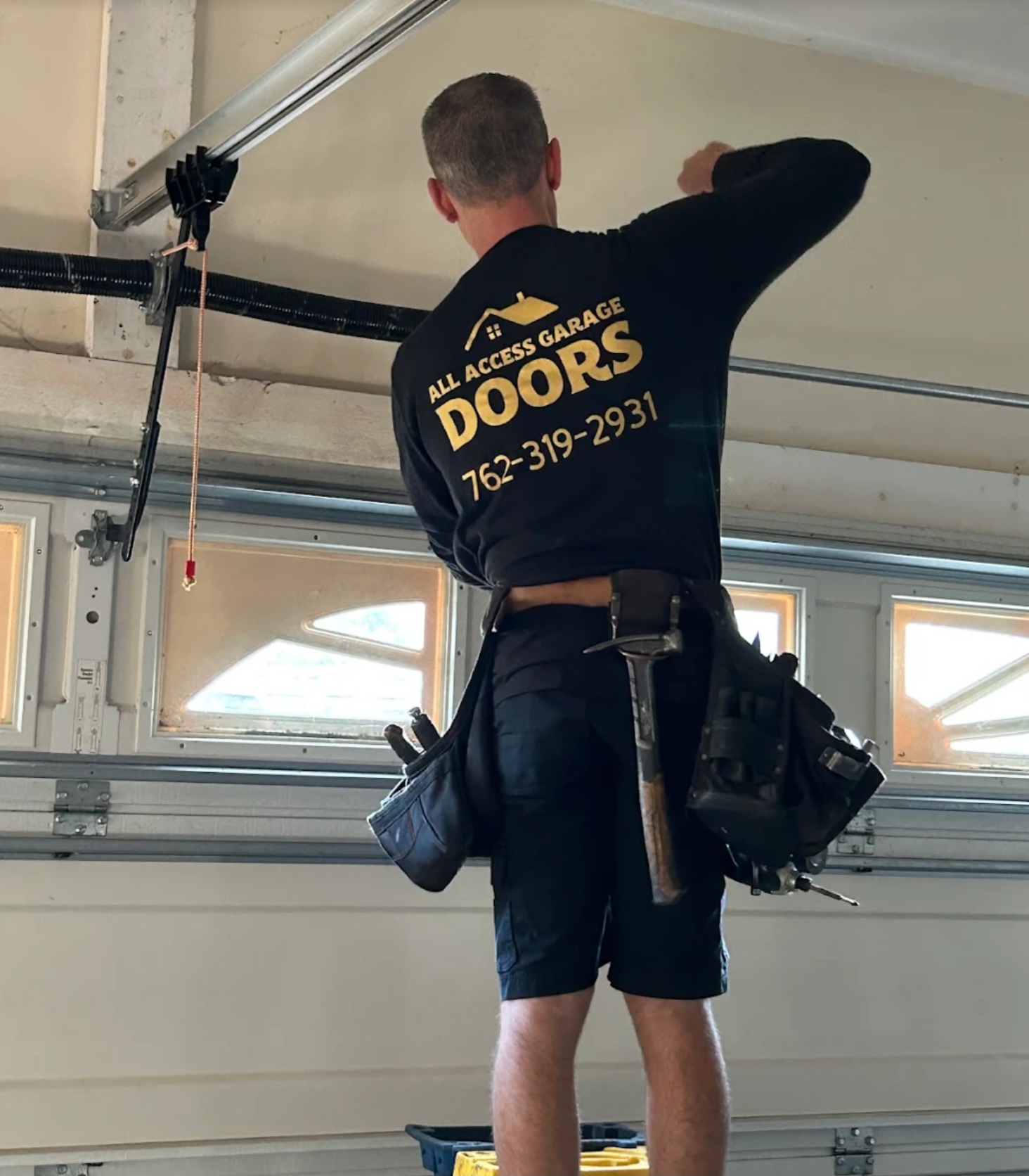 All Access Garage Doors technician repairing a broken torsion spring and lift cable on a residential garage door in Thomaston, GA