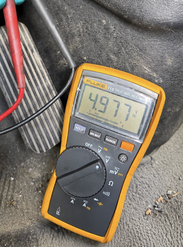 Solid Heavy Truck and Equipment Repair Ltd mobile diagnostics reading 4.977V on a Fluke 115 true RMS multimeter on-site