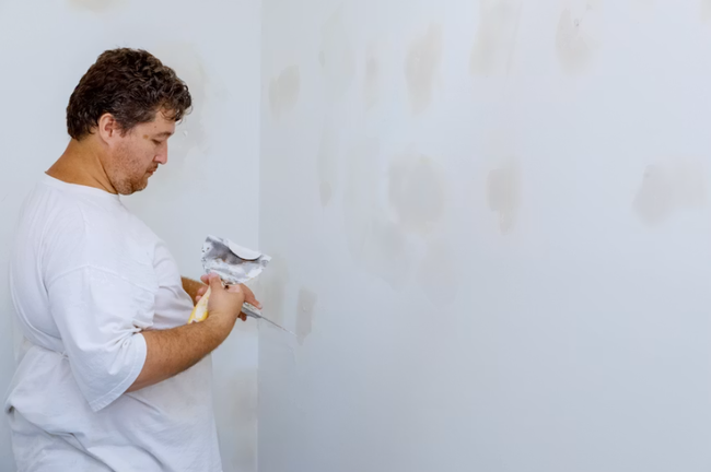 Drywall installation contractor applying joint compound to a newly hung gypsum wall panel in San Tan Valley, AZ