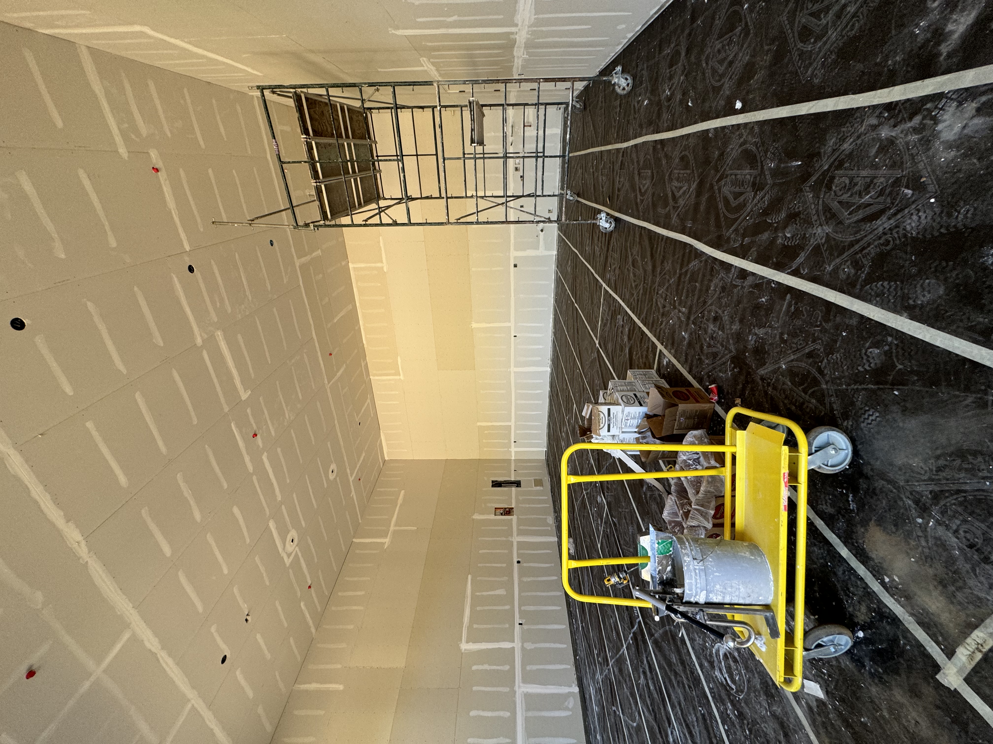 Drywall installation with taped seams, mudded fasteners, and high ceiling staging