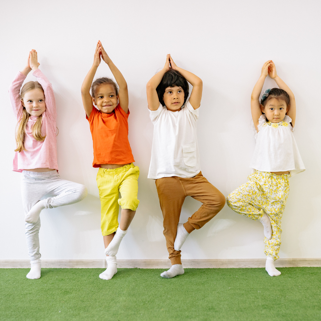 Children practicing tree pose together on a green mat
