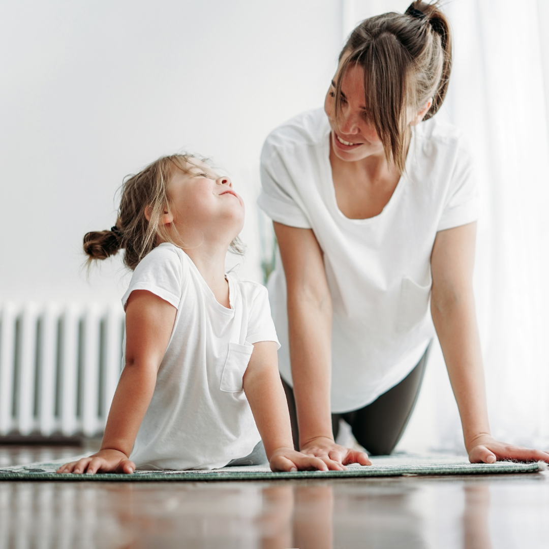 Teacher and young girl practicing cobra pose together