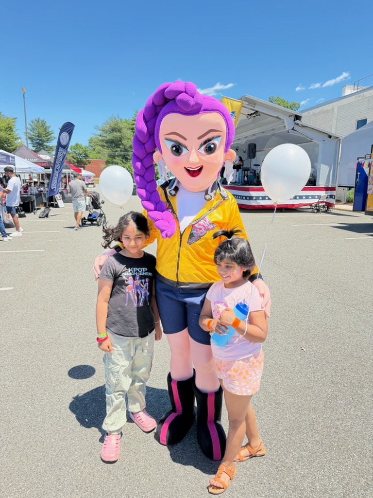 Kaleahs mascot performer with purple braided hair posing cheerfully with kids