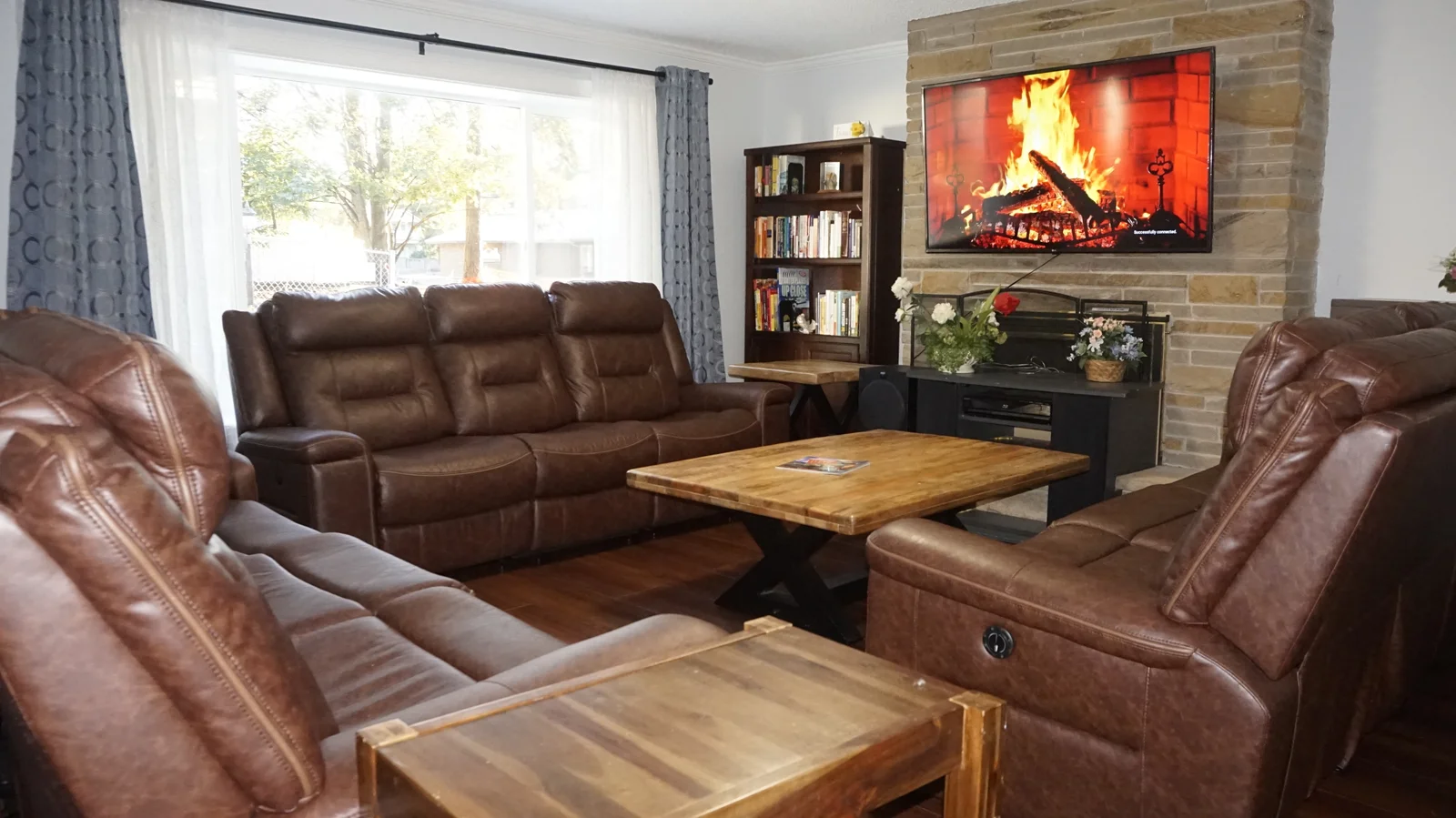 Avenue Home comfortable resident living room with cozy recliners, digital fireplace, and warm natural light
