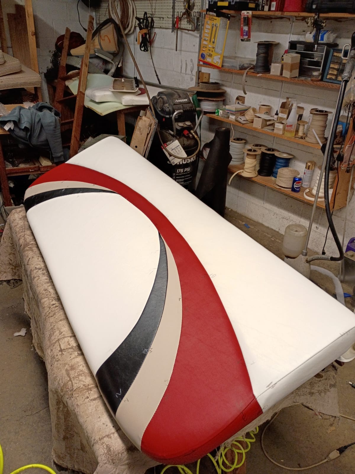 Custom marine and specialty vinyl bench cushion craft with red and black curved accent stripes
