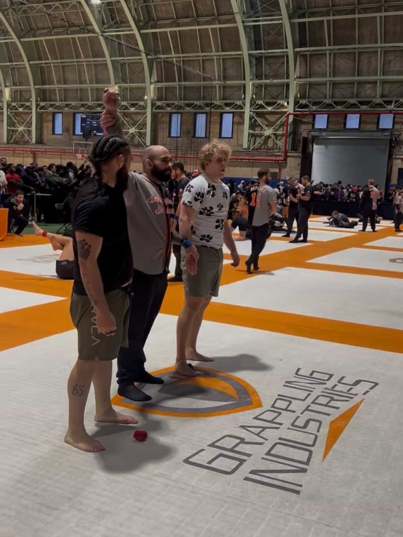 Fusion competitor with referee raising hand in victory at Grappling Industries tournament