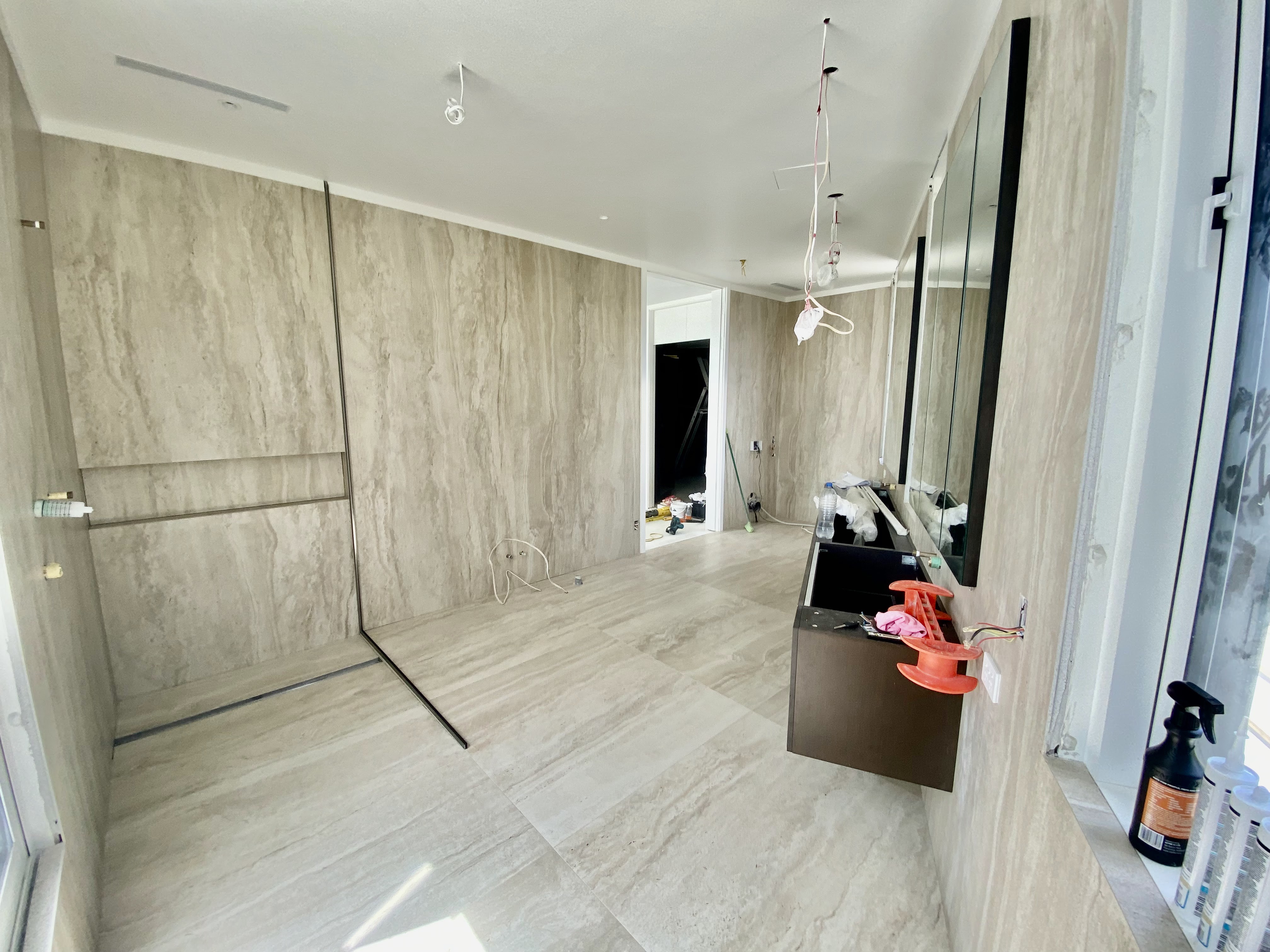 Full room floor-to-ceiling travertine tile installation with walk-in shower and integrated niche.