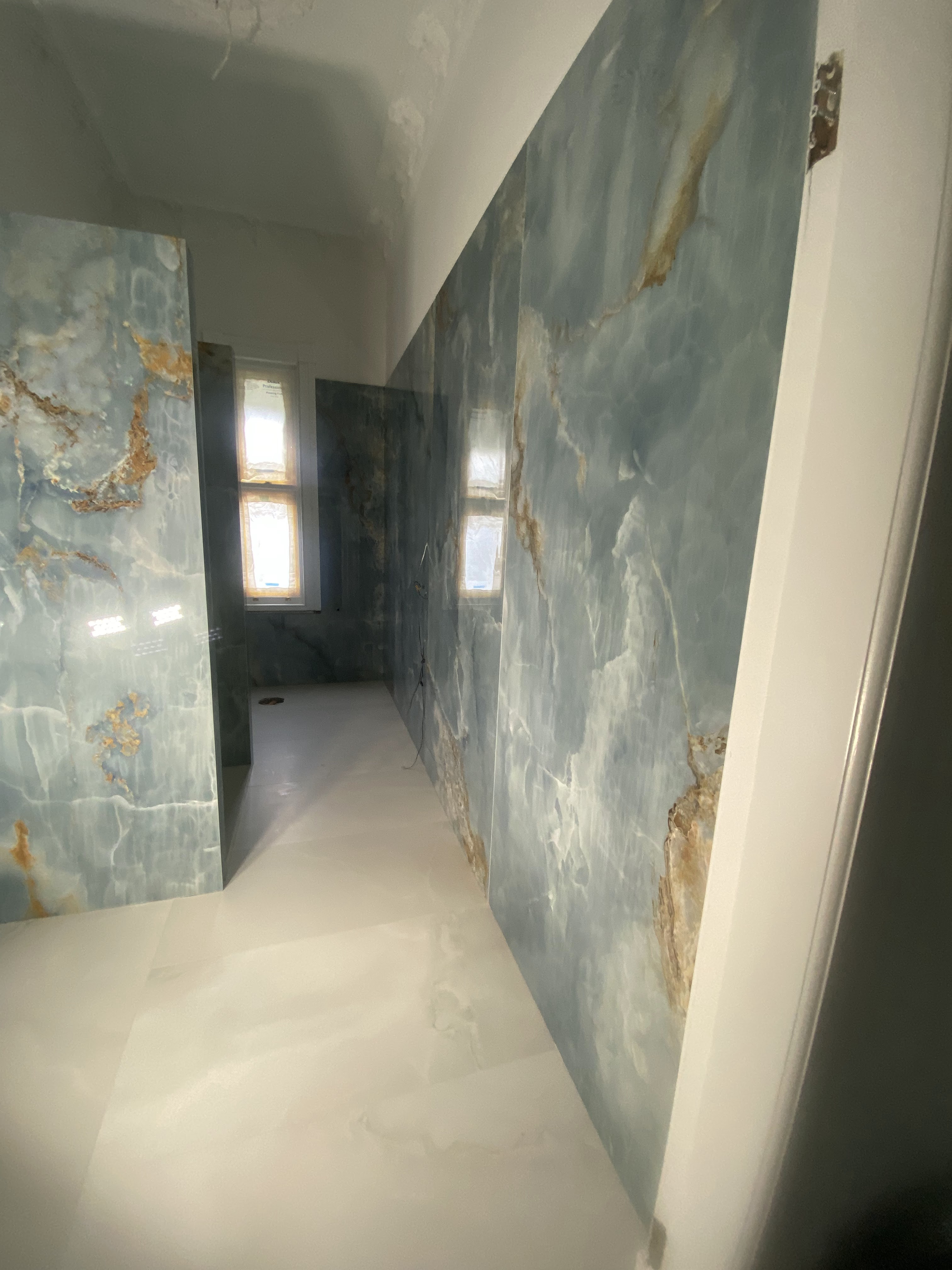 Bookmatched blue marble large-format porcelain slab bathroom feature walls.