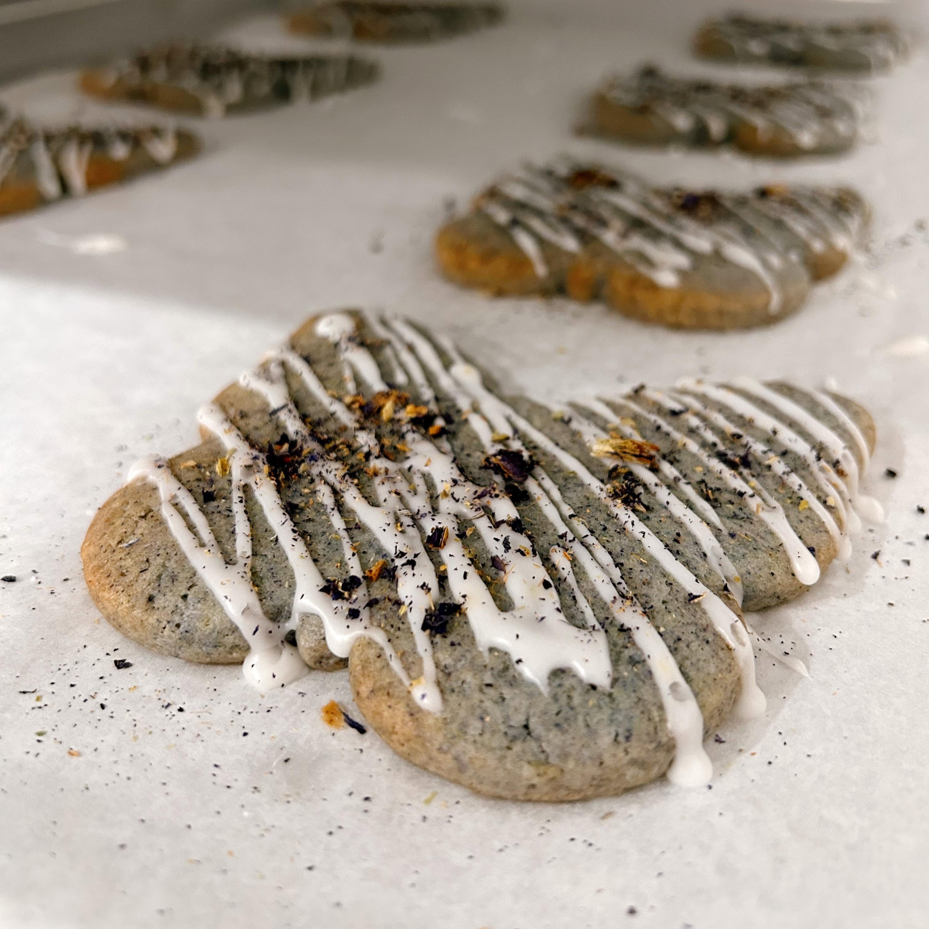Artisanal butterfly-shaped iced shortbread cookies with royal icing and dried farm flower petals