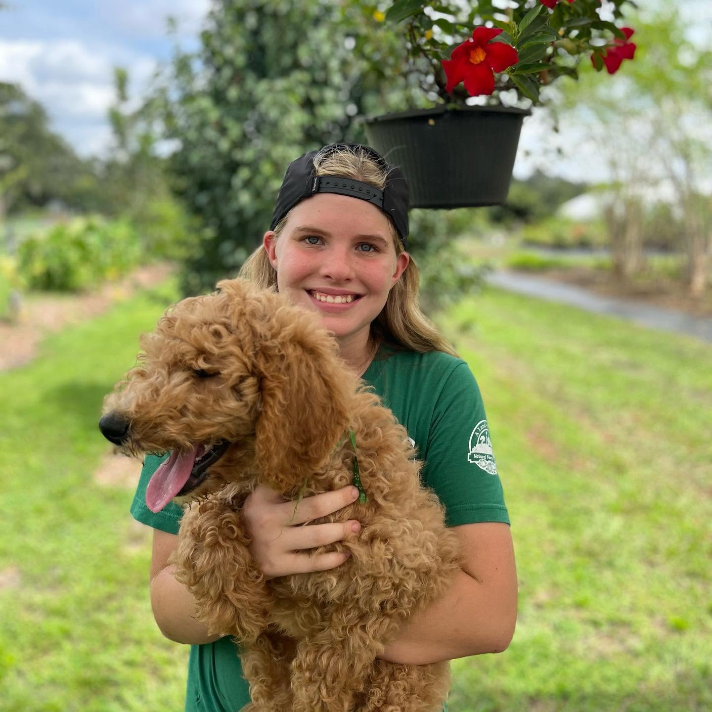 Farm family member smiling and hugging a fluffy golden puppy at A Land of Delight farm nursery