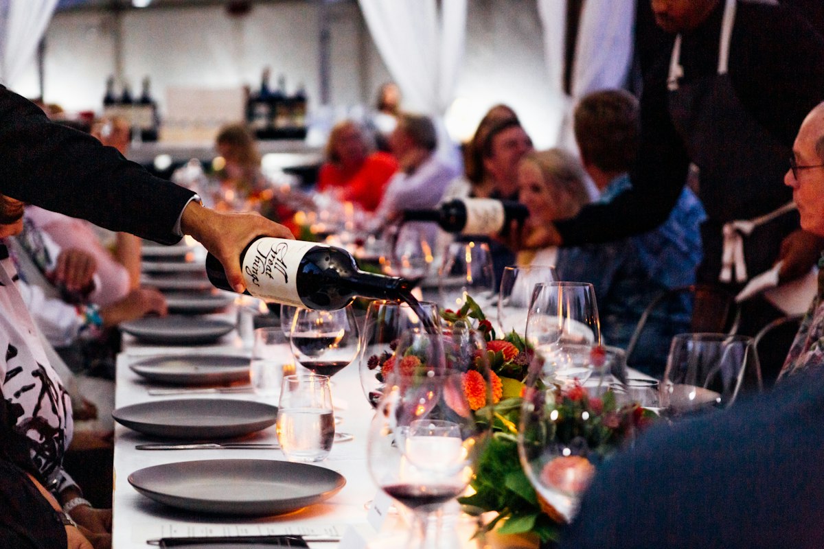 A server pouring wine for a group seated at a long private dining table