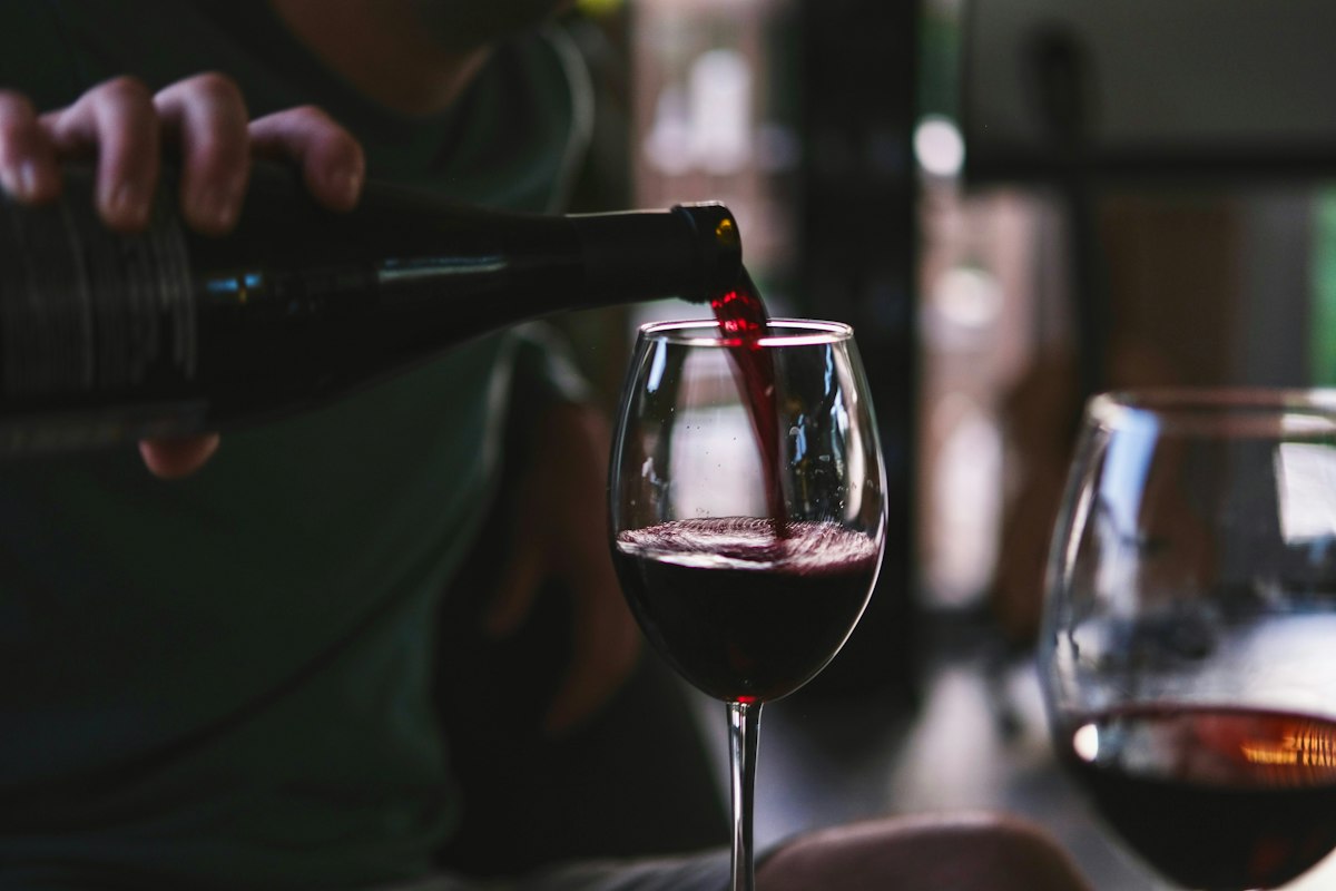 Red wine being poured into a glass during a pairing dinner