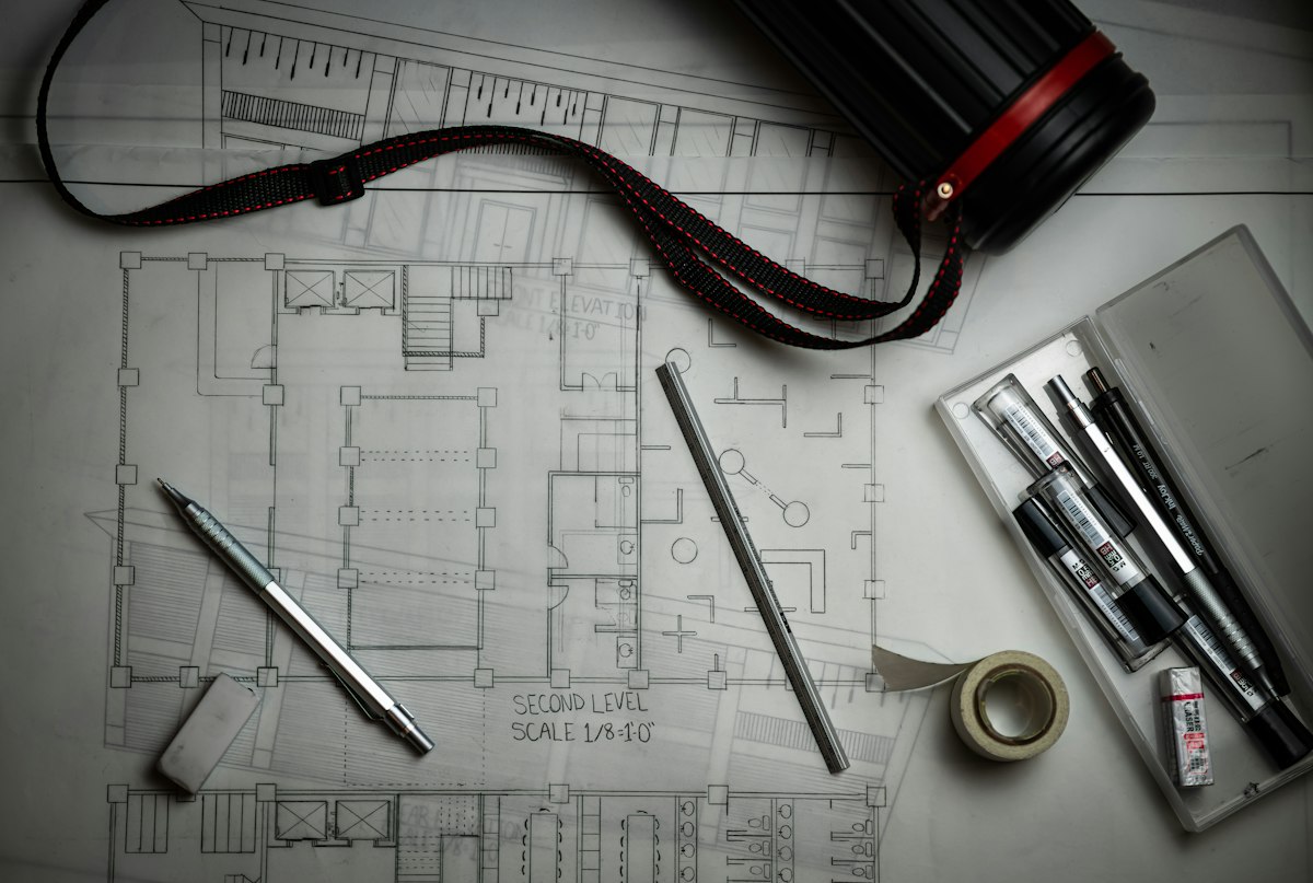 Architectural house plans with drafting tools on a desk